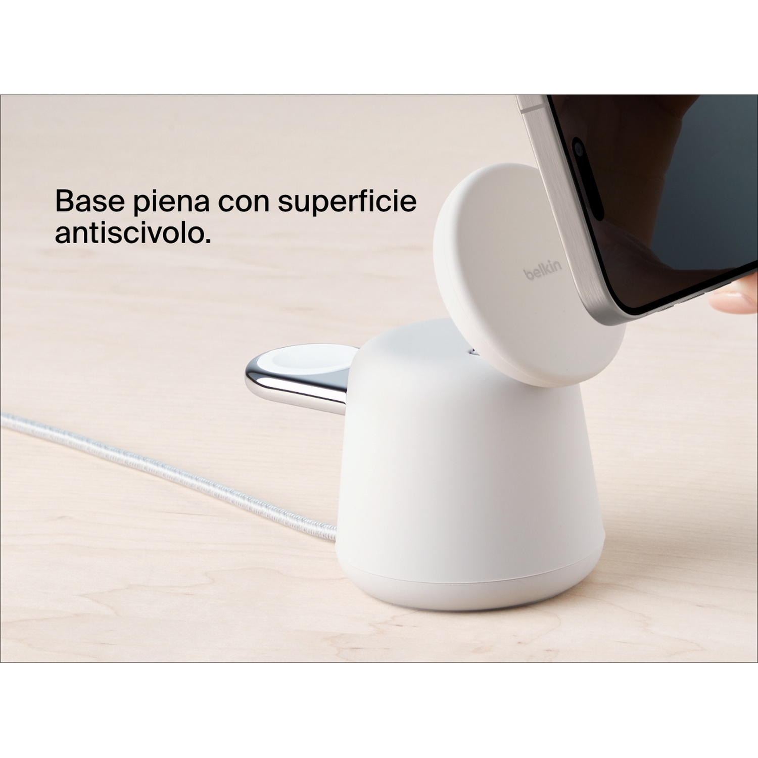 Eine weiße Belkin-Kabellos-Ladestation auf Holzoberfläche, an der ein Smartphone angebracht wird.