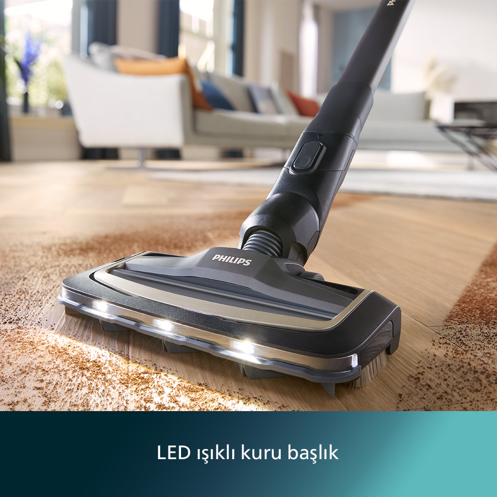 LED ışıklı Philips süpürge başlığı, aydınlık bir oturma odasında ahşap zemindeki kalıntıları temizliyor.