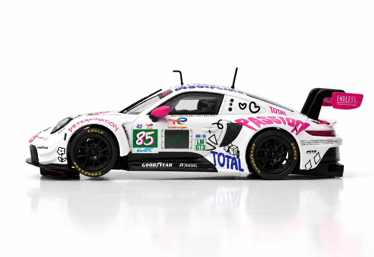 Un coche de carreras blanco con pegatinas coloridas como PASSION y el número 85 sobre fondo blanco.