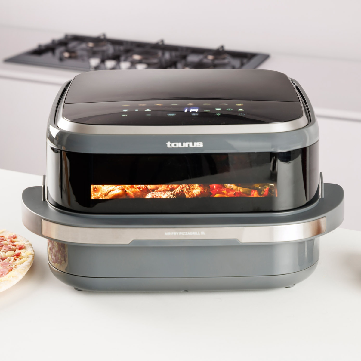 Freidora de aire gris Taurus Air Fry Pizza Grill XL en una encimera de cocina con interior iluminado.