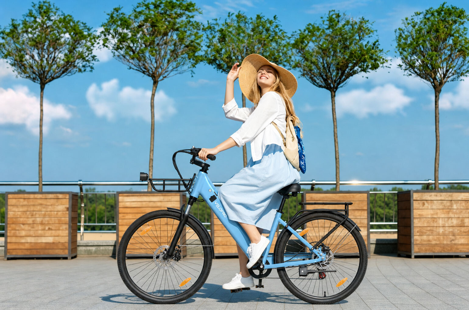 Eine Frau mit Strohhut und weißem Hemd fährt ein hellblaues Fahrrad vor Bäumen und blauem Himmel.