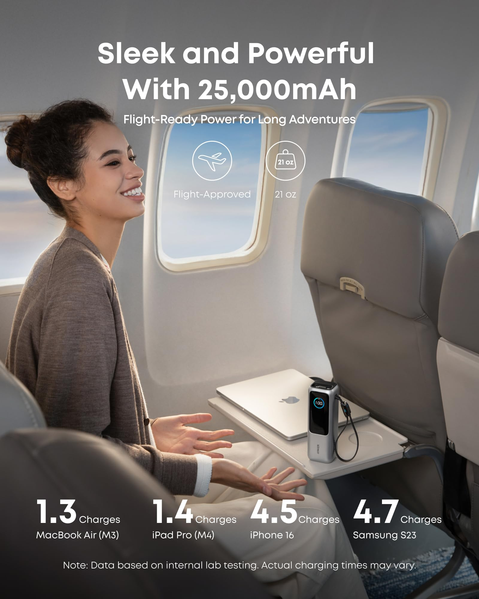 Mujer sonriente en un asiento de avión junto a una mesita con batería y portátil.