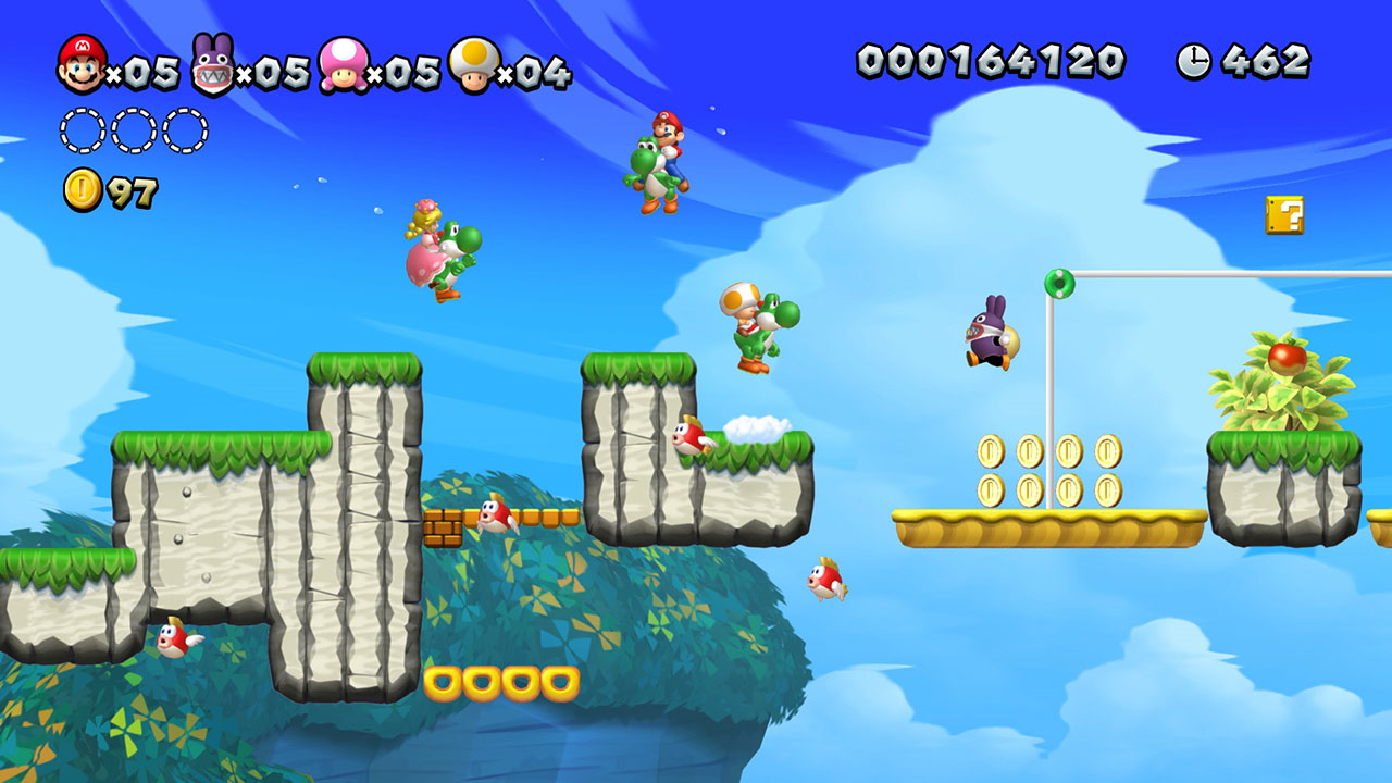 I personaggi di Mario cavalcano Yoshi in un colorato livello di gioco con nuvole e monete.