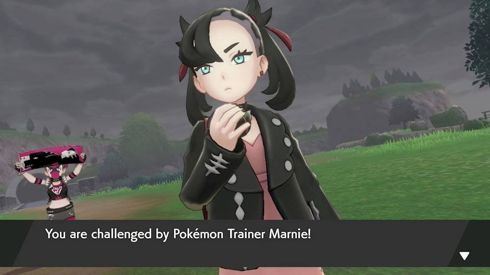 L'allenatrice Pokémon Marnie ti sfida alla lotta, con un fan del Team Yell sullo sfondo.