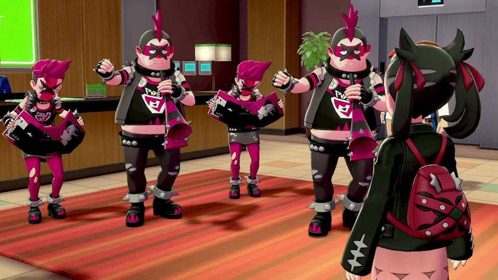 Quattro personaggi punk con capelli rosa e maschere affrontano un allenatore con uno zaino rosso in un edificio.