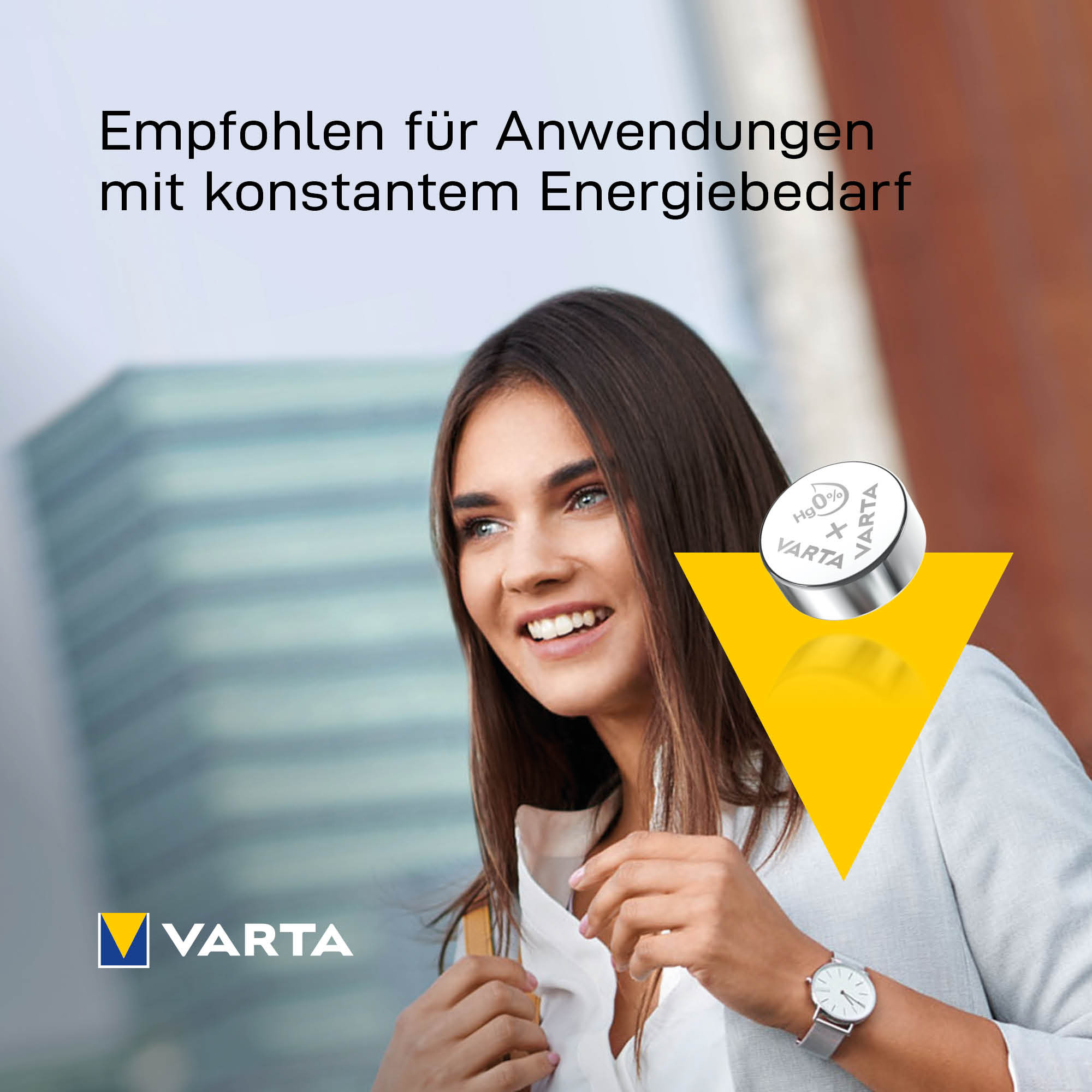 Lächelnte Frau vor einem Gebäude mit Varta-Knopfzelle und gelbem Dreieck.