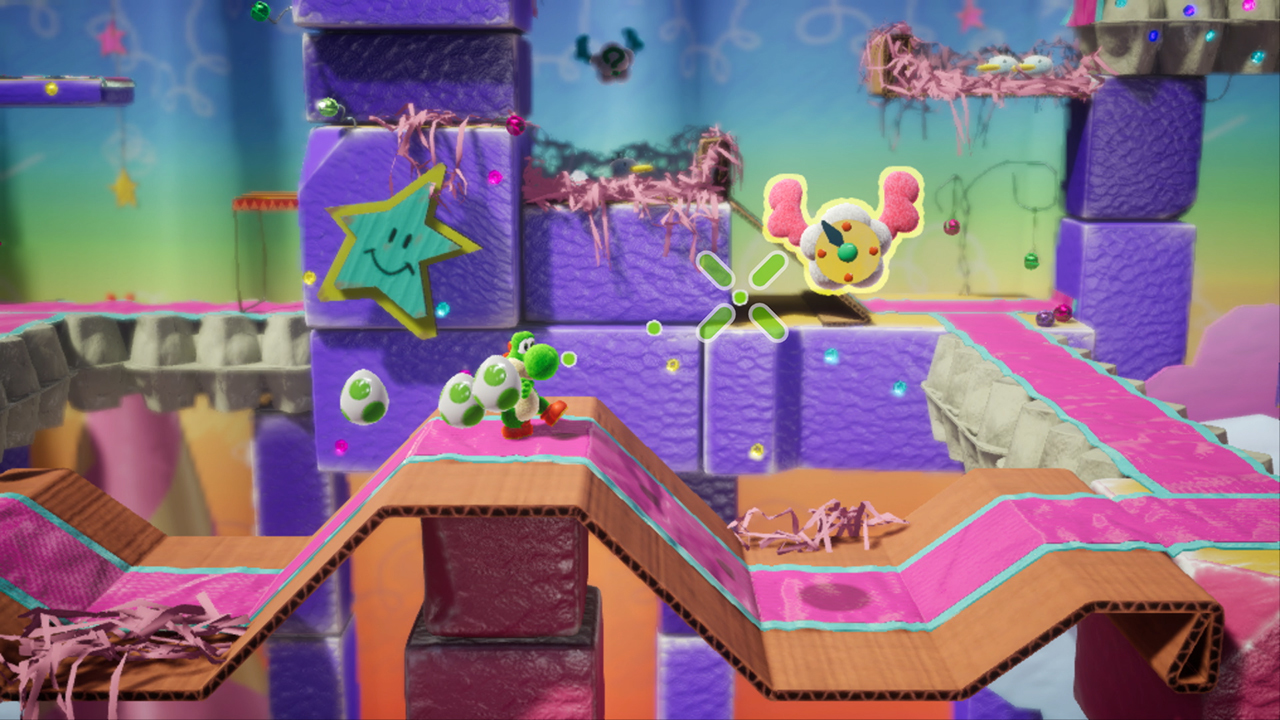 Yoshi verde lleva un huevo en un mundo colorido hecho de cartón y tela.