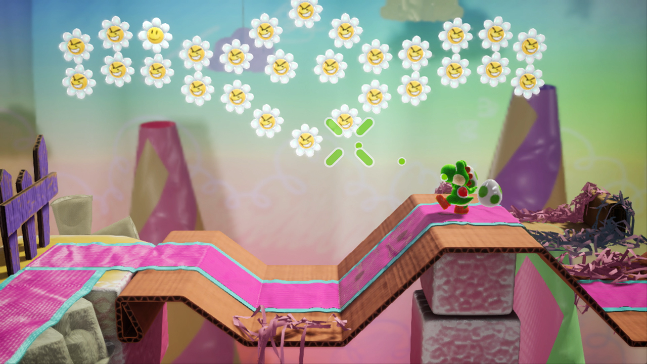 Yoshi verde en un camino de cartón ondulado con franjas rosas bajo flores flotantes.