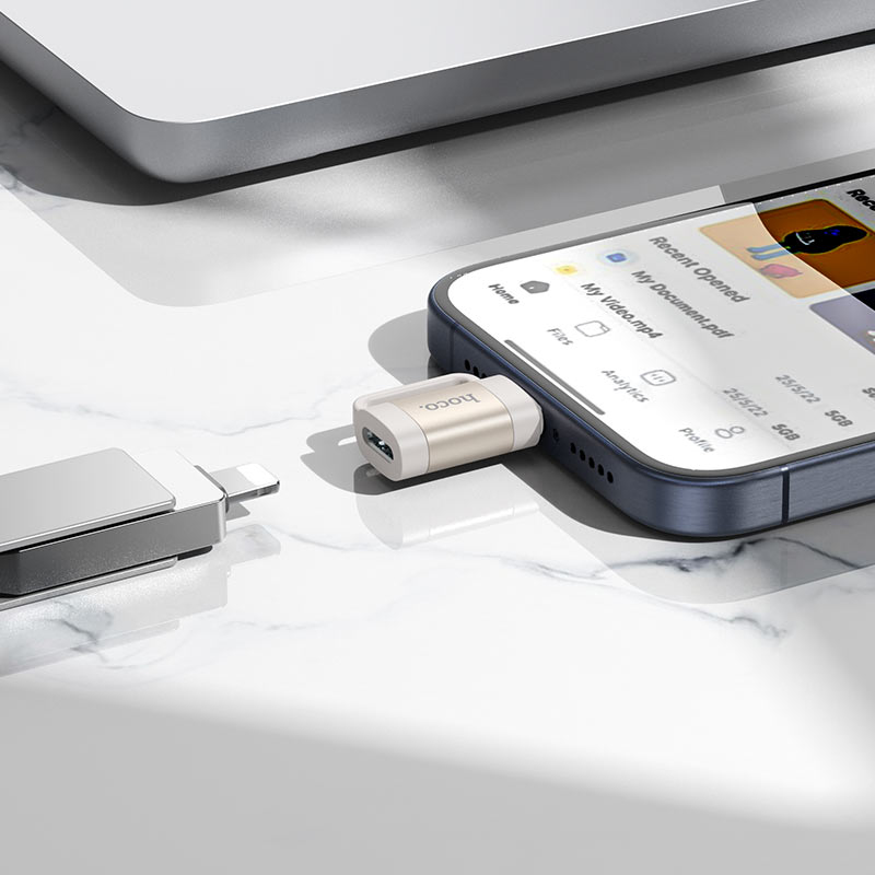 Ein Smartphone mit USB-Adapter und Flash-Laufwerk auf einem weißen Tisch.