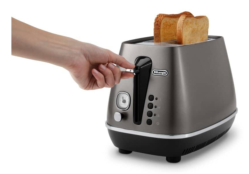 Una mano preme la leva di un tostapane grigio DeLonghi, con due fette di pane tostato.