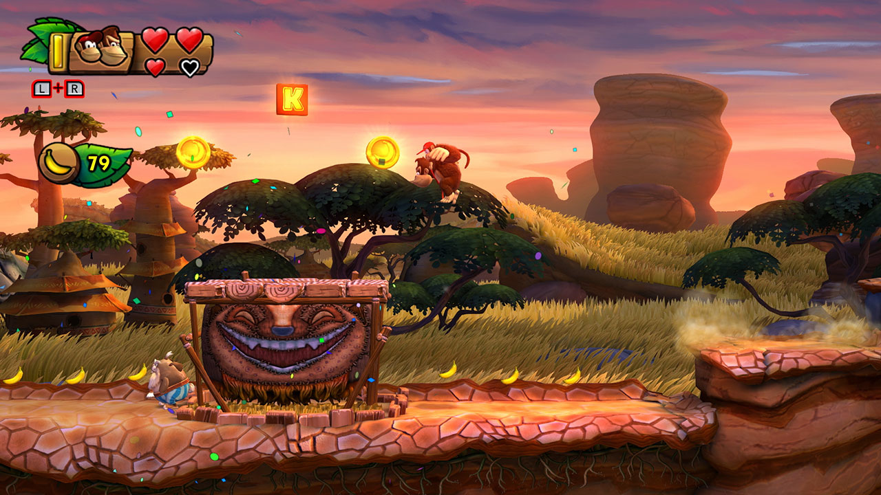 Schermata di gioco Donkey Kong con personaggio su un albero, monete e tamburo intagliato al tramonto.