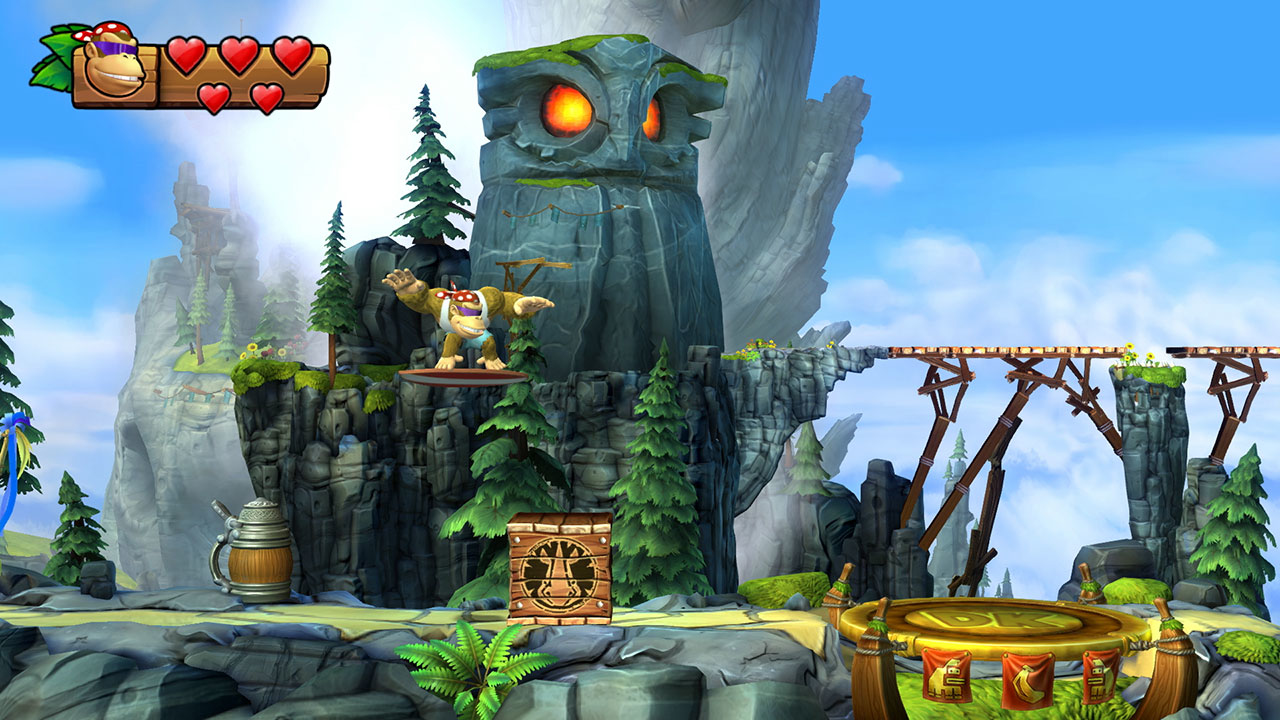 Una scimmia salta davanti a una statua di gufo rocciosa nel videogioco Donkey Kong Country: Tropical Freeze.