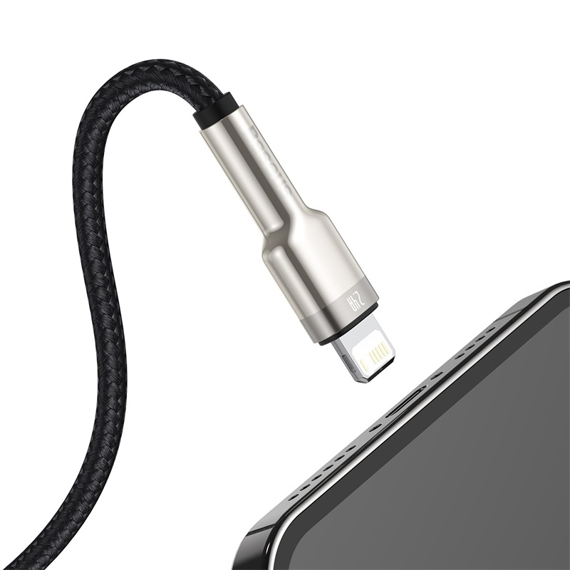Un cable USB negro trenzado se acerca al puerto de carga de un teléfono inteligente.