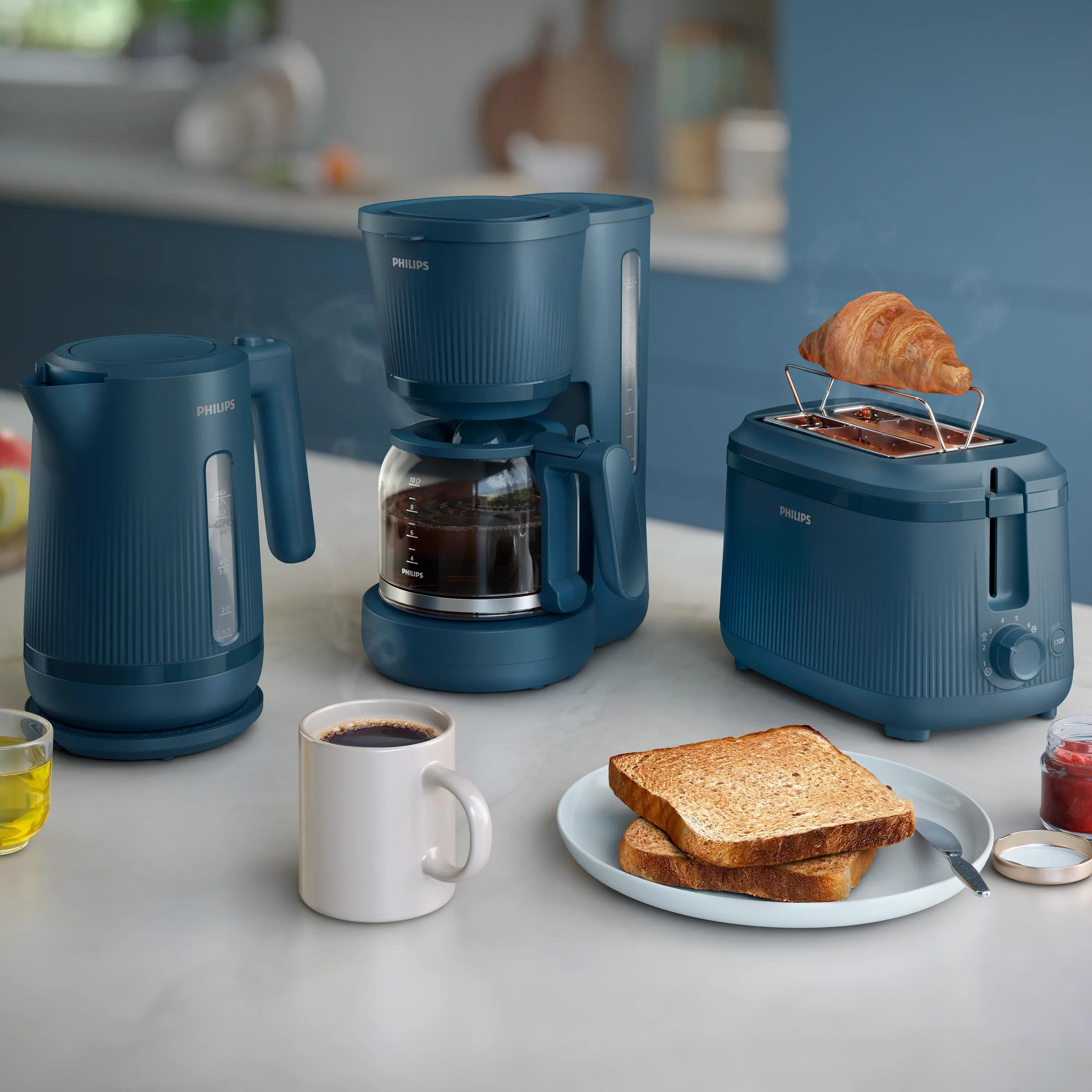 Blauwe Philips keukenapparaten op een aanrecht met koffie, toast en een croissant.