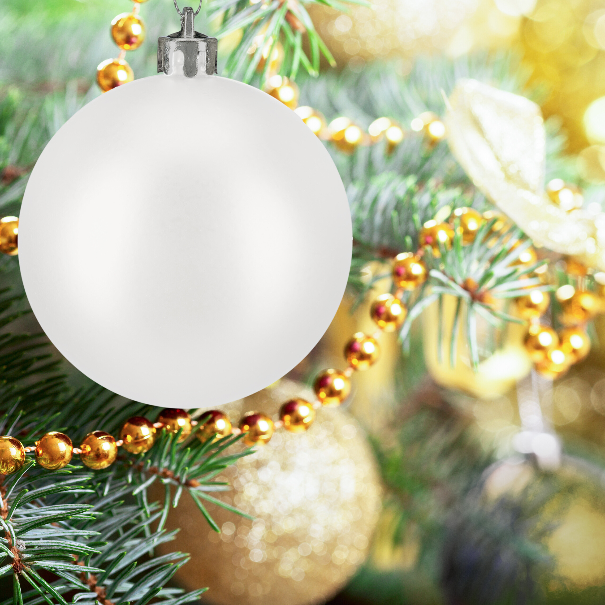 Eine matte weiße Weihnachtskugel hängt an einem Weihnachtsbaum mit goldenen Perlenketten.