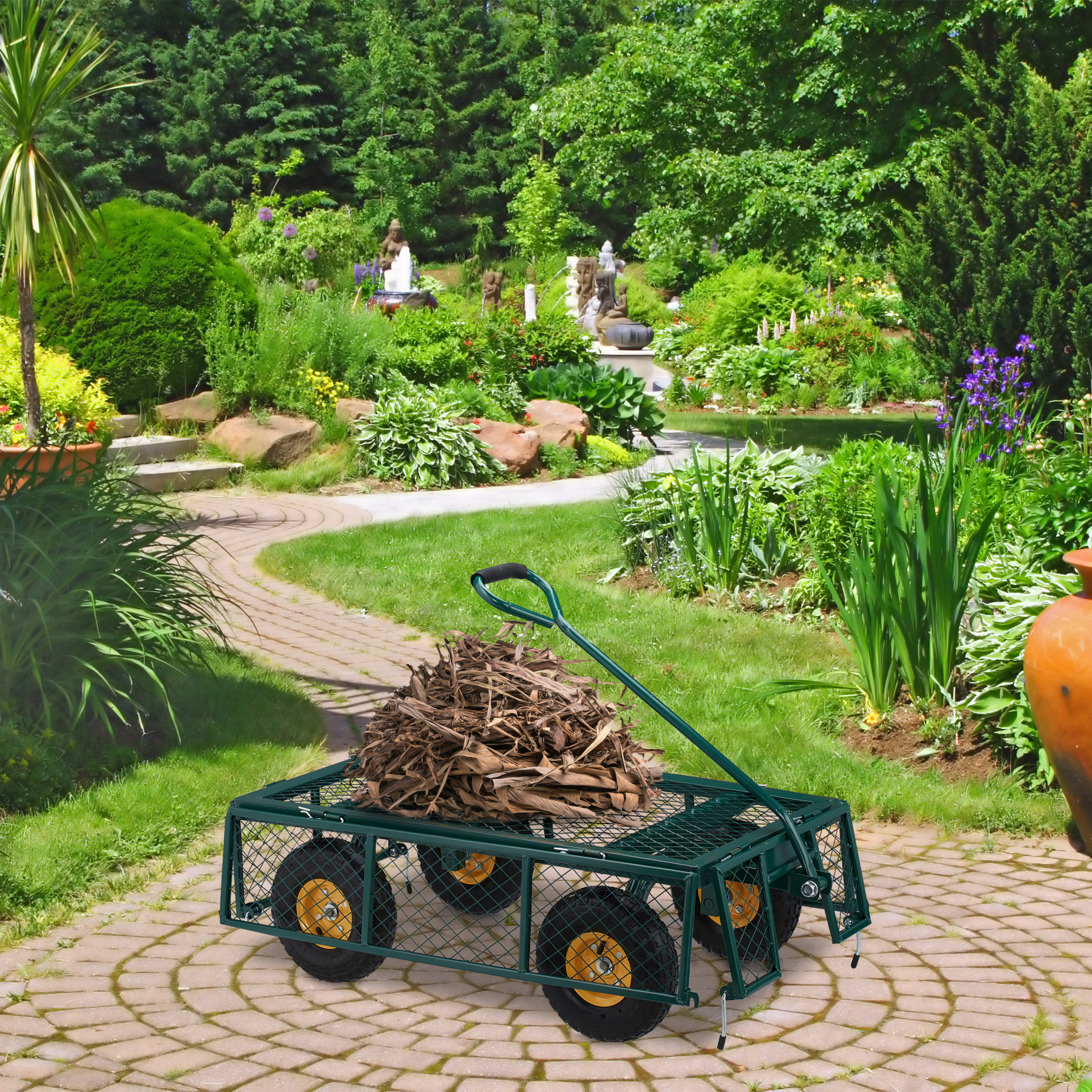 Ein grüner Gartenwagen voller trockener Blätter steht auf einem Steinweg im üppigen Garten.