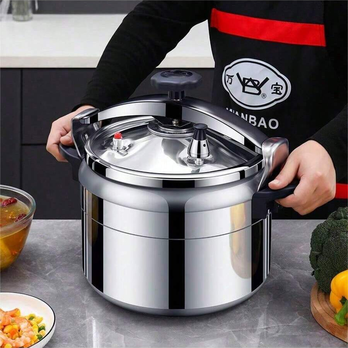 Persona sosteniendo una olla a presión de acero inoxidable grande y brillante en una cocina.