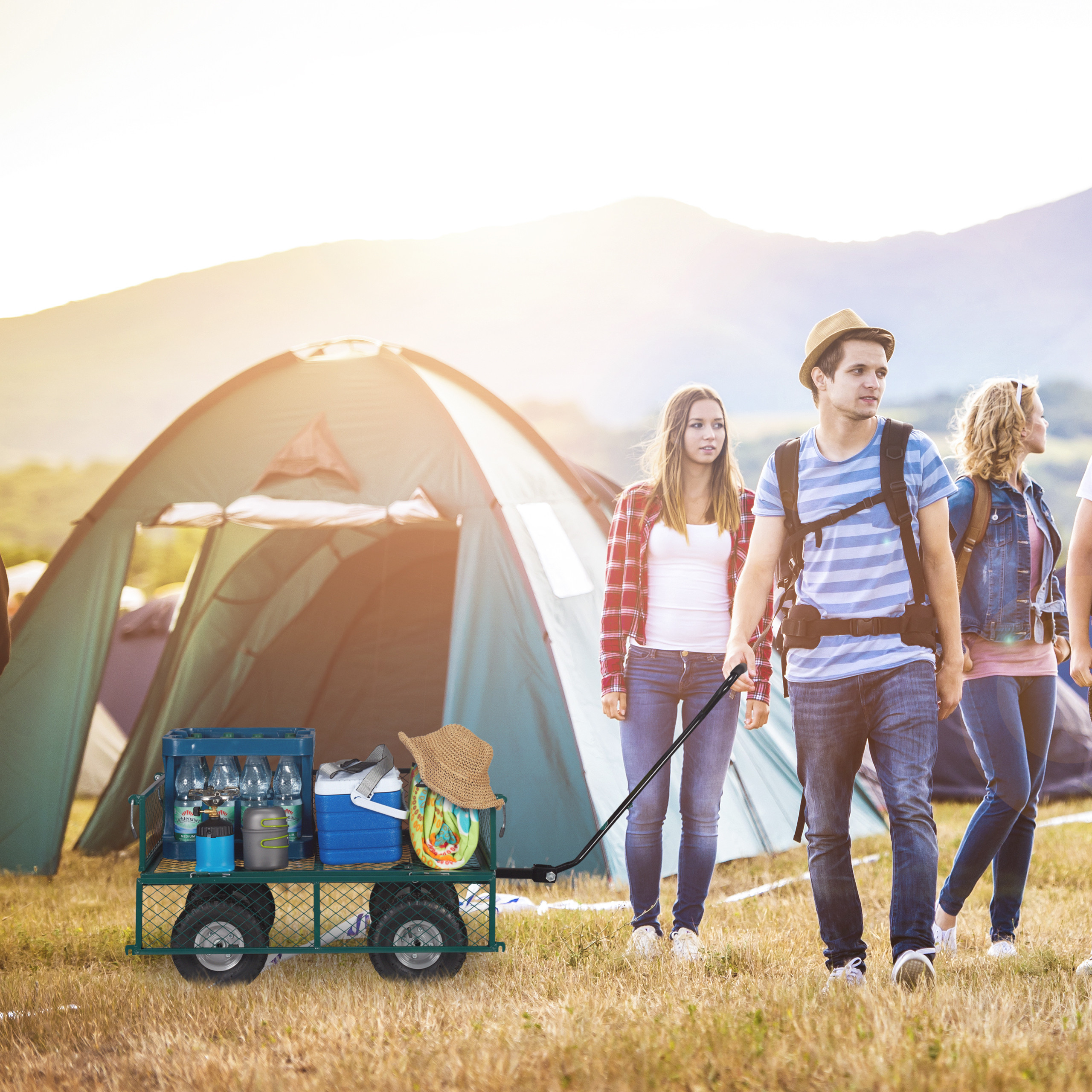 Freunde beim Camping, ziehen einen Handwagen mit Ausrüstung vor einem großen Zelt.