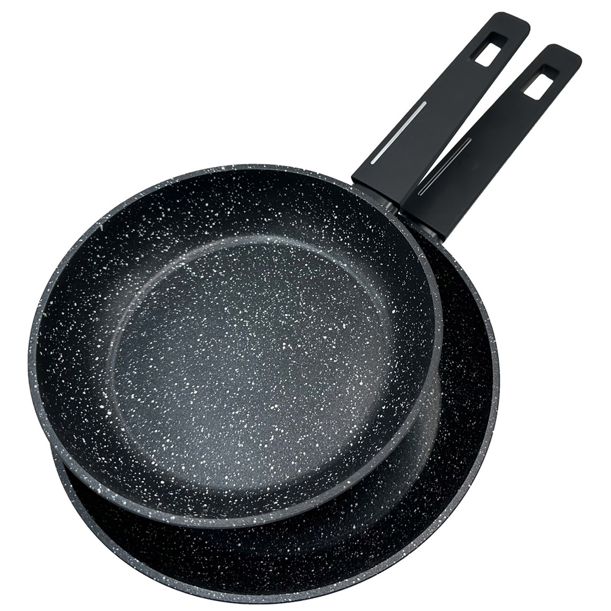 Dos sartenes negras con motas y mangos largos están apiladas sobre un fondo blanco.