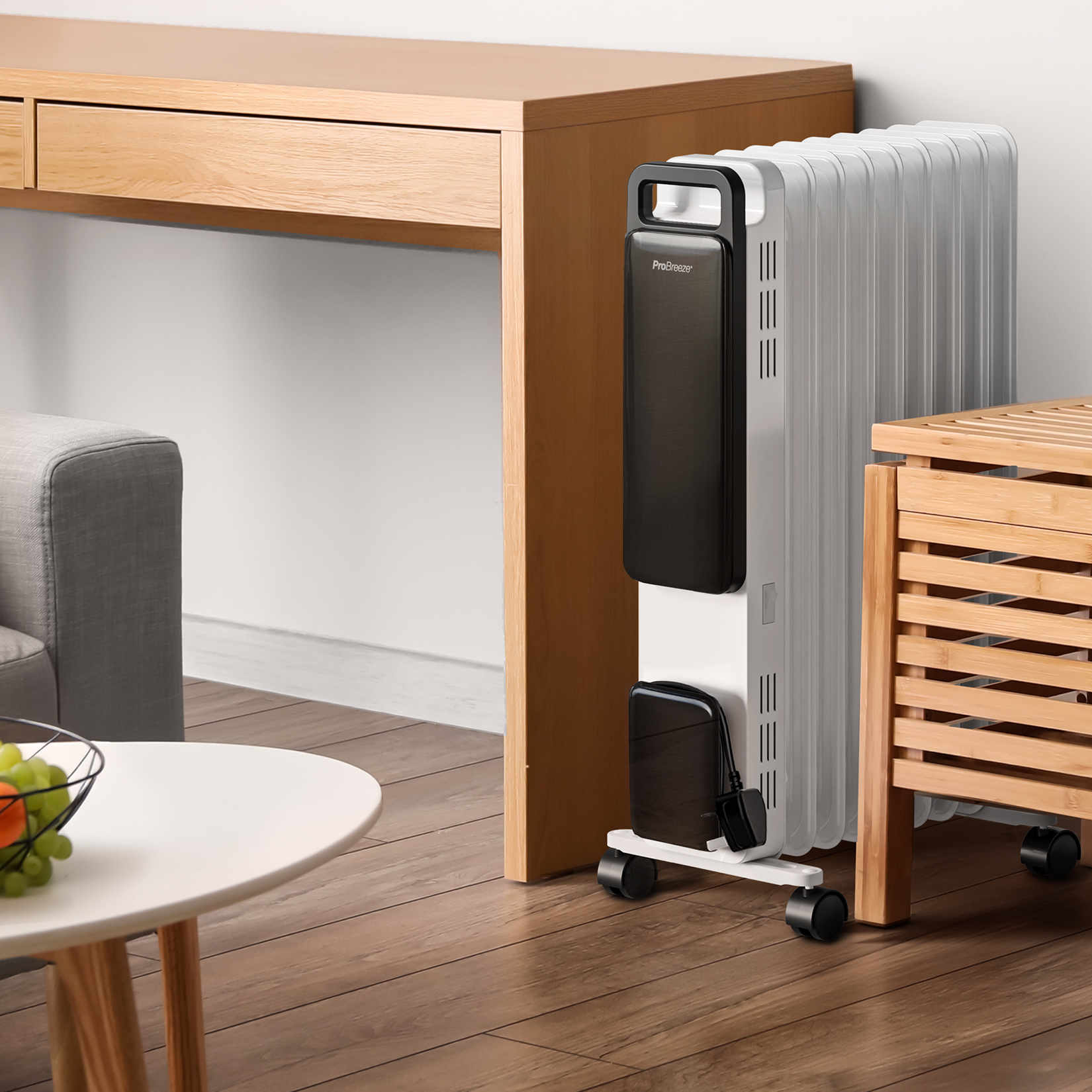 Ein weißer Pro Breeze Radiator steht auf Rädern im Raum, neben einem Holztisch.