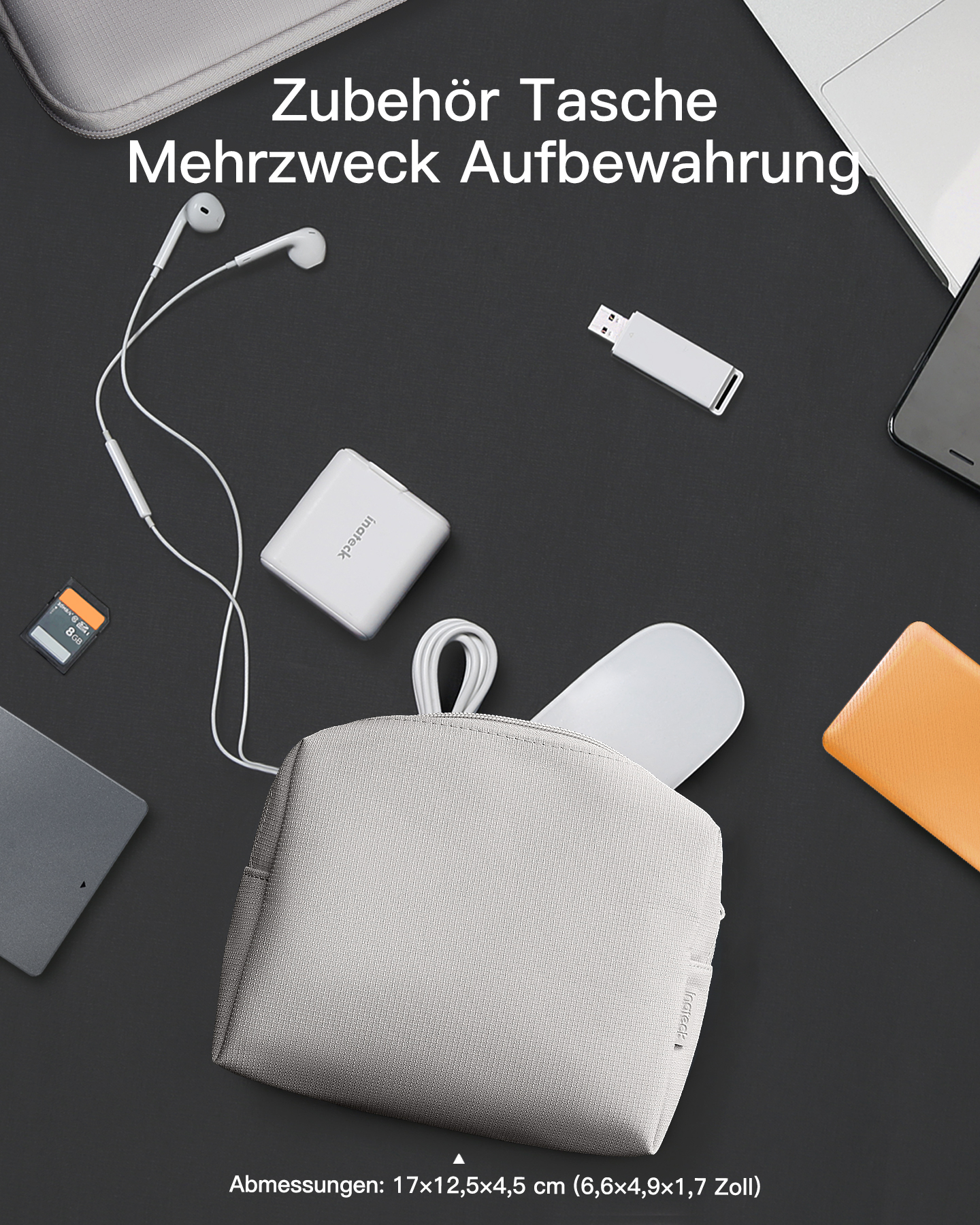 Eine graue Zubehörtasche auf schwarzem Tisch mit Kopfhörern, Ladekabeln, USB-Stick und weiteren Elektronikartikeln.