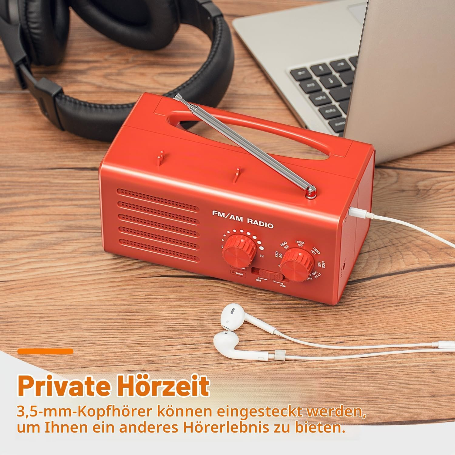 Ein rotes FM/AM-Radio auf einem Holztisch mit Kopfhörern und Laptop.