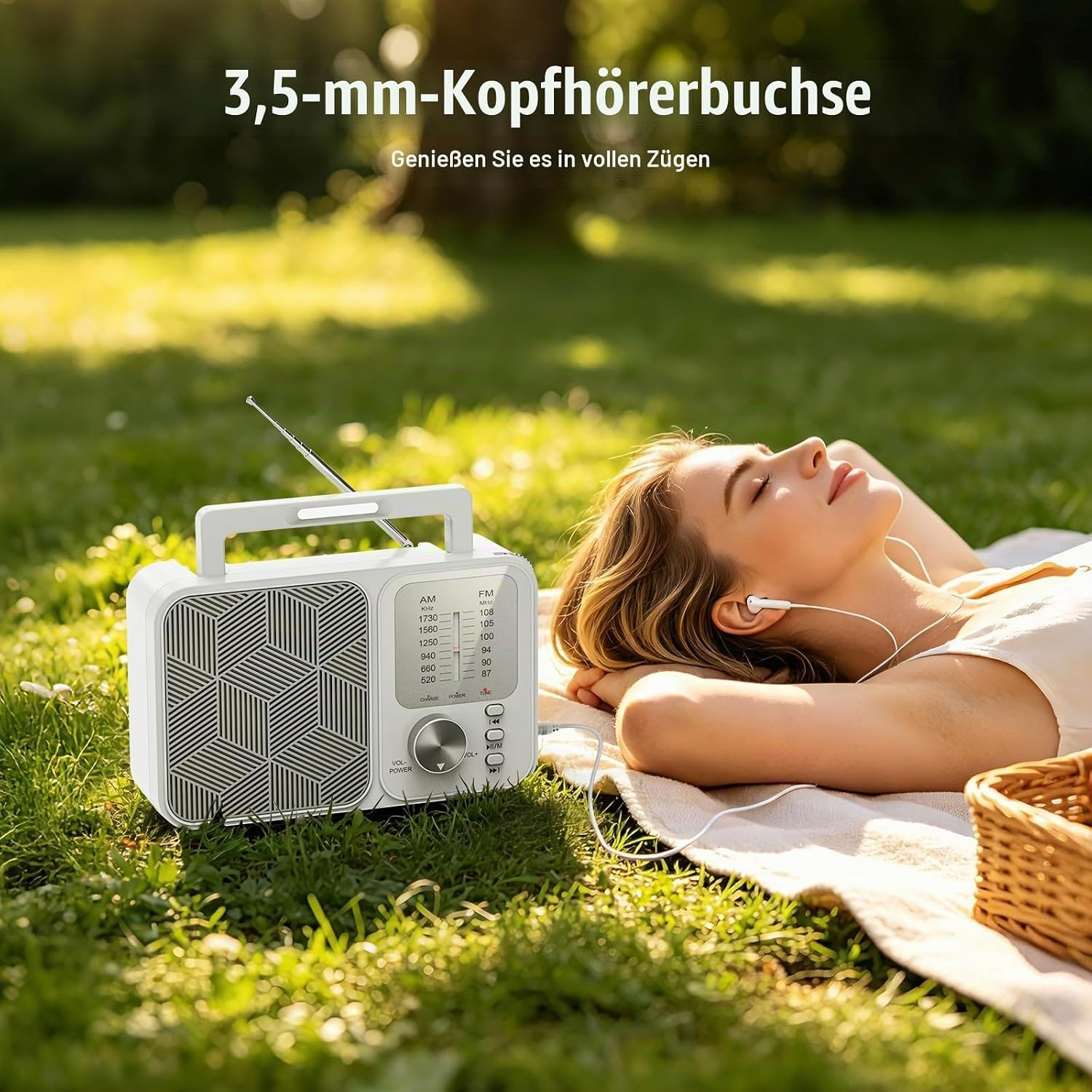 Eine Frau entspannt draußen auf einer Picknickdecke und hört Musik über Kopfhörer, die mit einem weißen Radio verbunden sind.