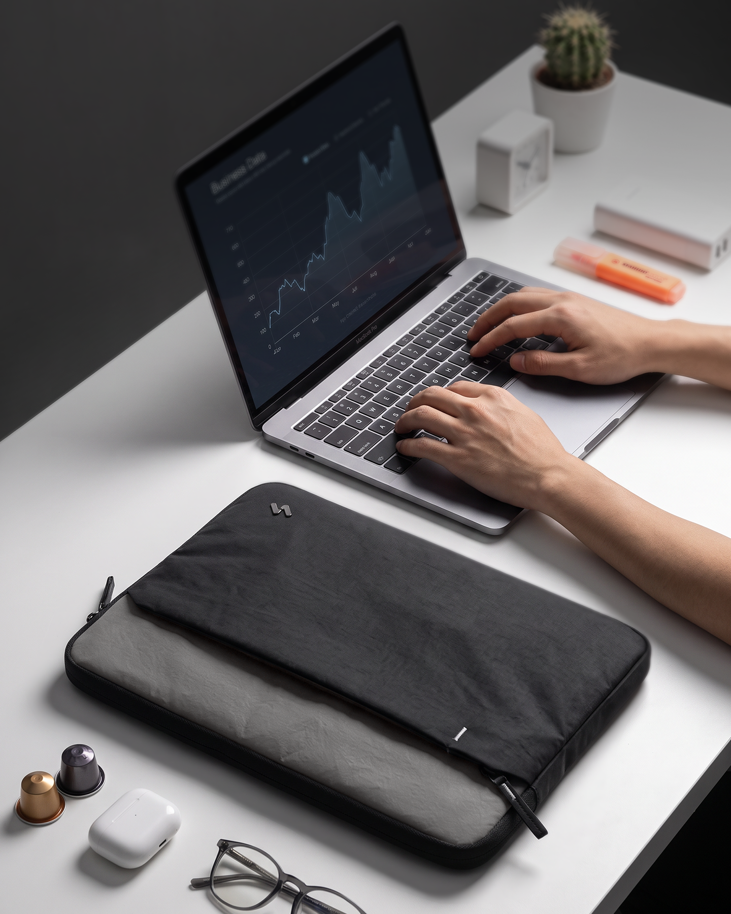 Ein Laptop mit Diagrammen auf dem Bildschirm steht auf einem Schreibtisch, davor eine Laptoptasche.