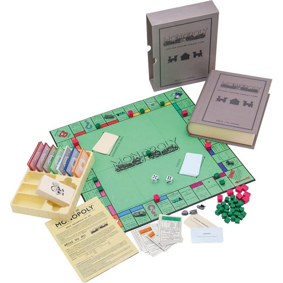 Ein Vintage-Monopoly-Spiel mit grünem Brett, Box im Buchdesign, Karten, Würfeln sowie roten und grünen Häusern.