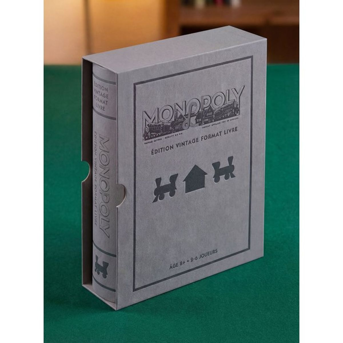 Eine graue Monopoly Vintage-Buch-Edition Box auf einem grünen Tisch.