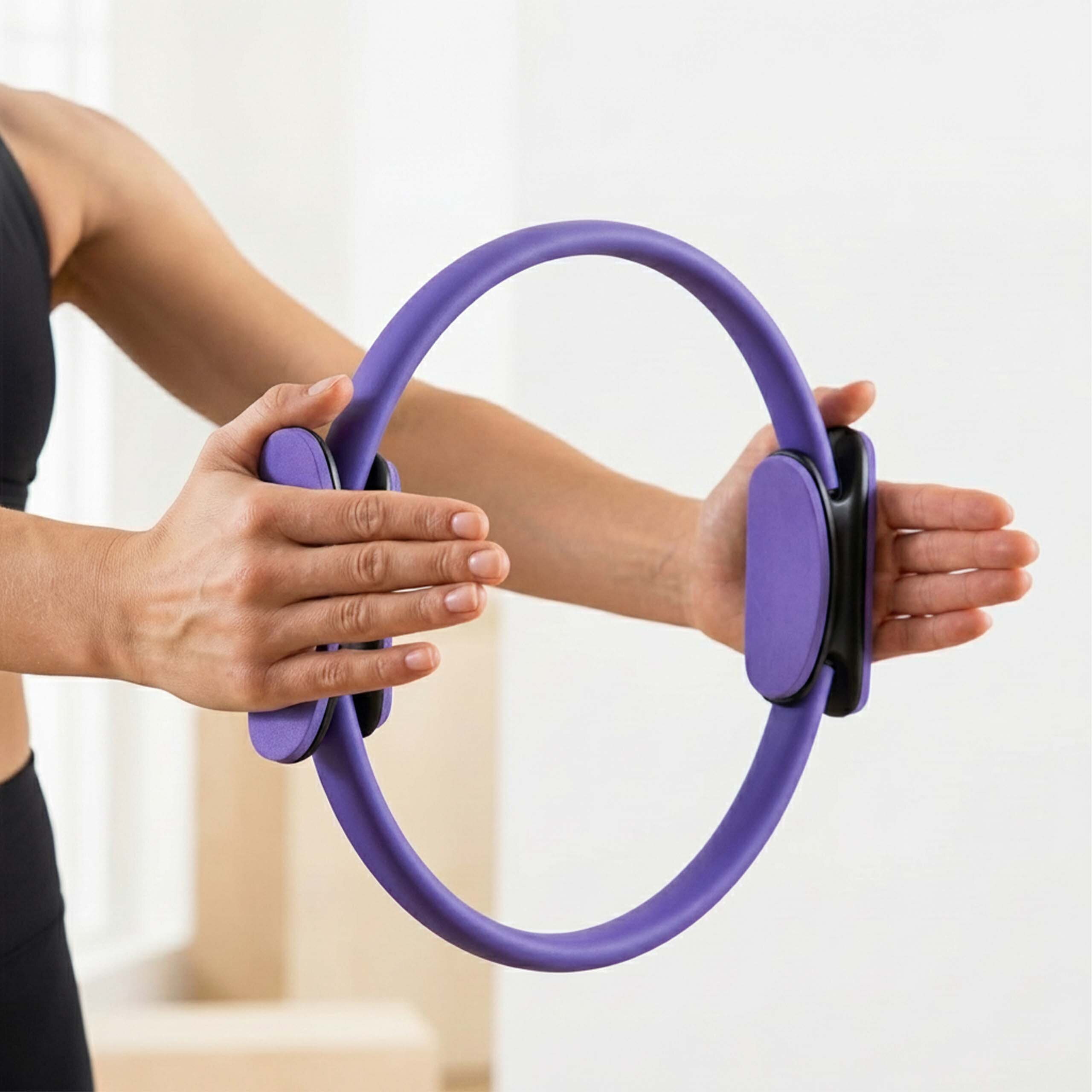 Eine Frau hält einen violetten Pilates-Ring mit beiden Händen vor sich.