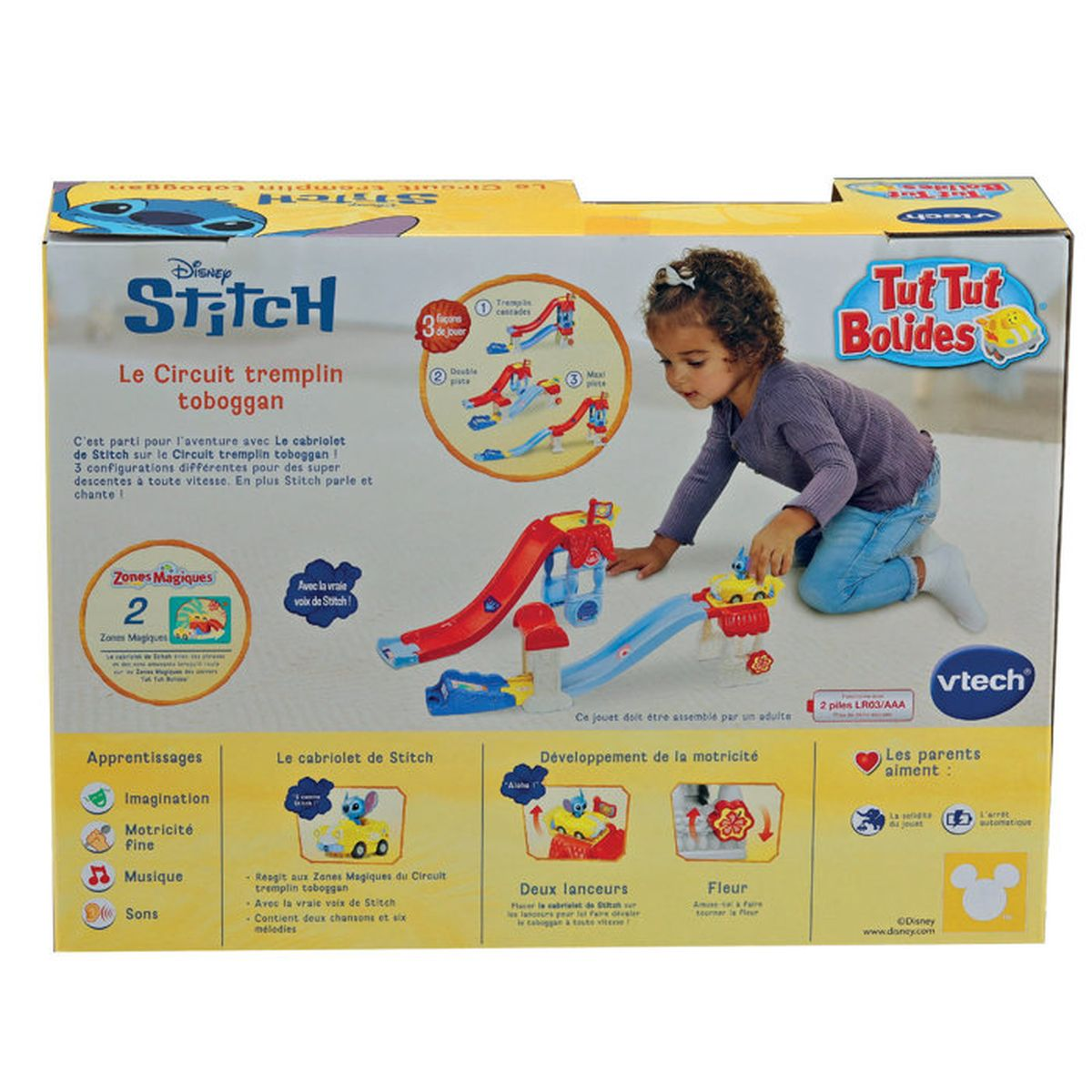 Ein kleines Mädchen spielt mit einer bunten VTech Stitch Spielzeugauto-Rennstrecke auf der gelben Verpackung.