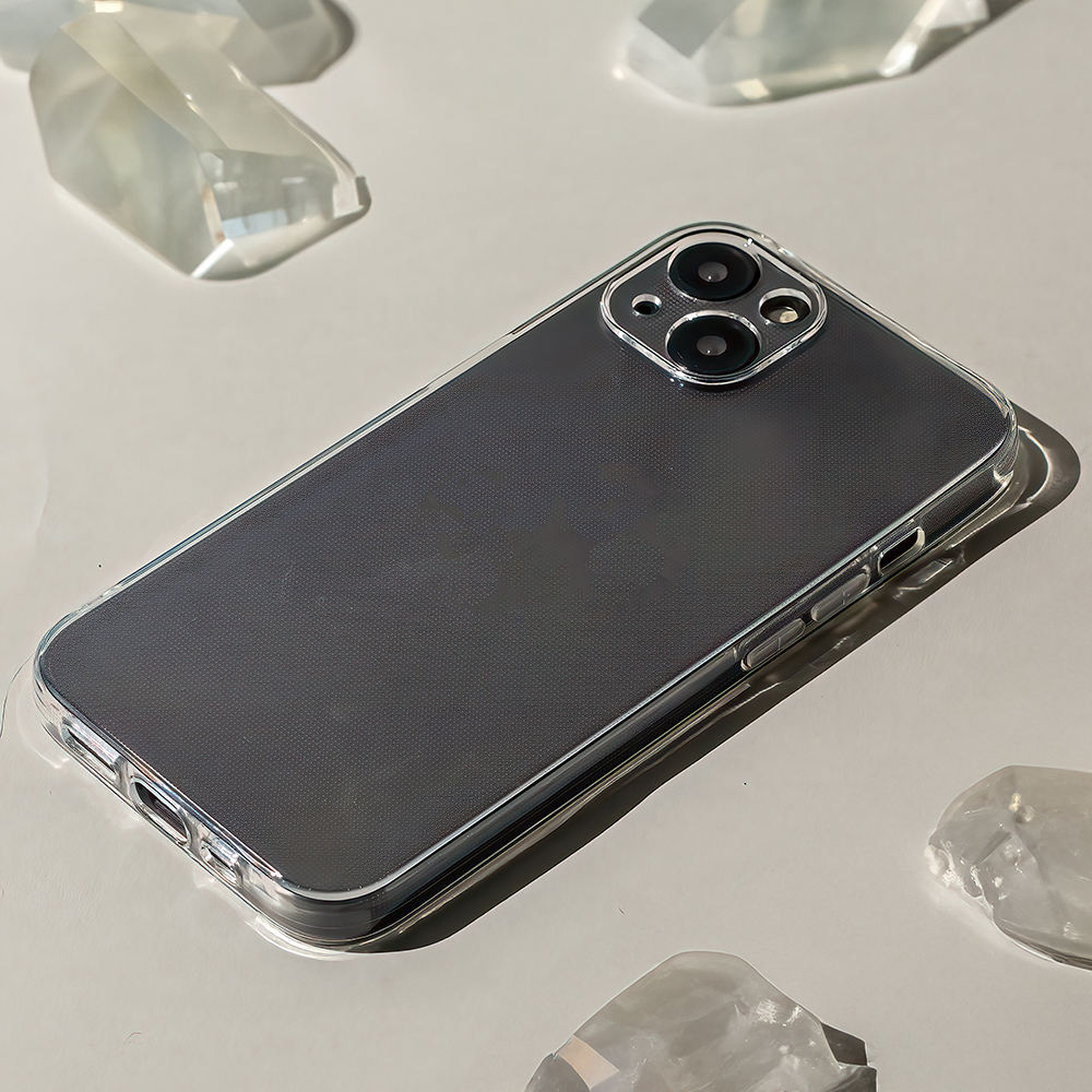 Ein Smartphone mit grauer Rückseite und transparenter Hülle liegt auf heller Oberfläche neben Kristallstücken.