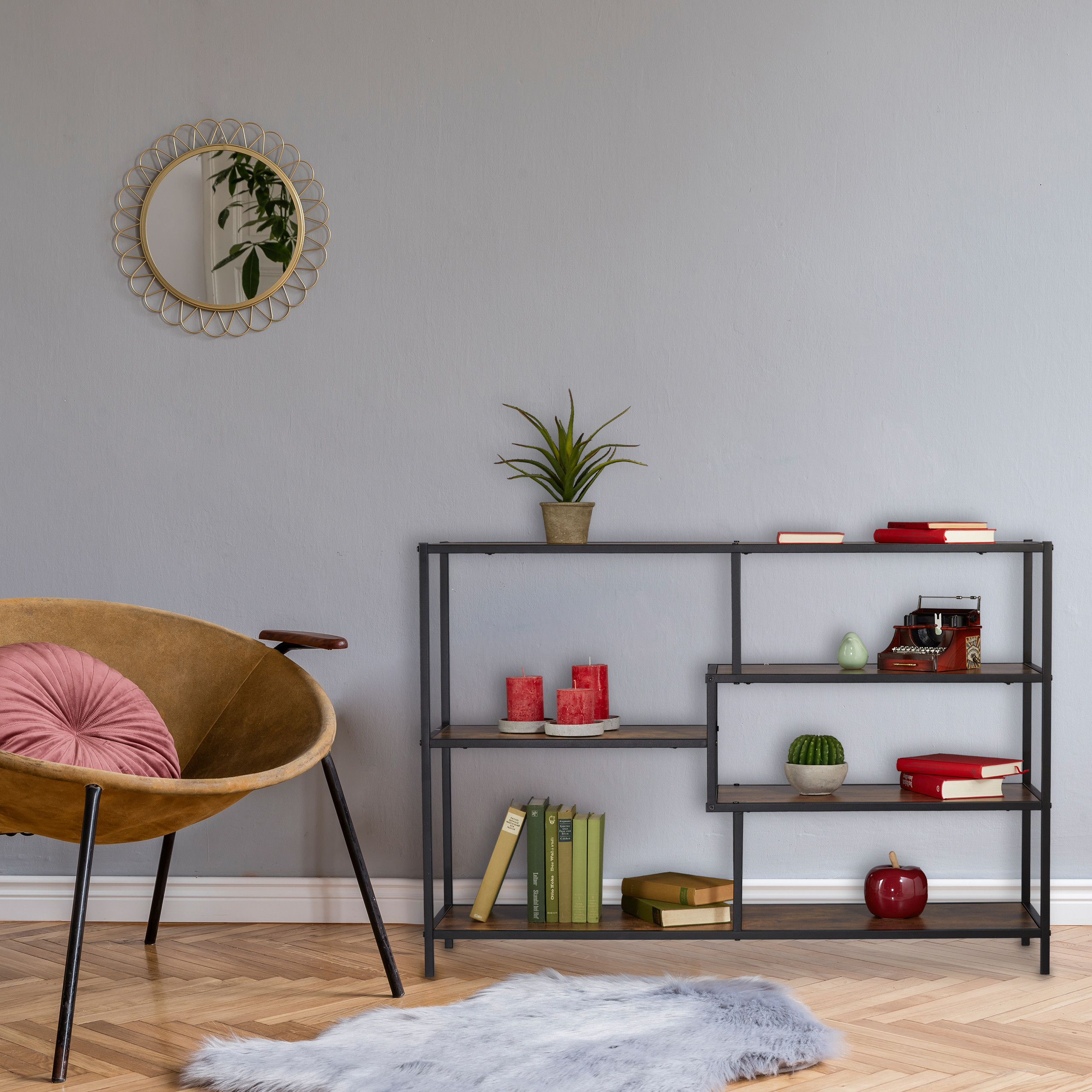 Stilvolles Zimmer mit grauem Wand, Holzboden, gelbem Sessel mit Kissen, schwarzem Regal und rundem Spiegel.
