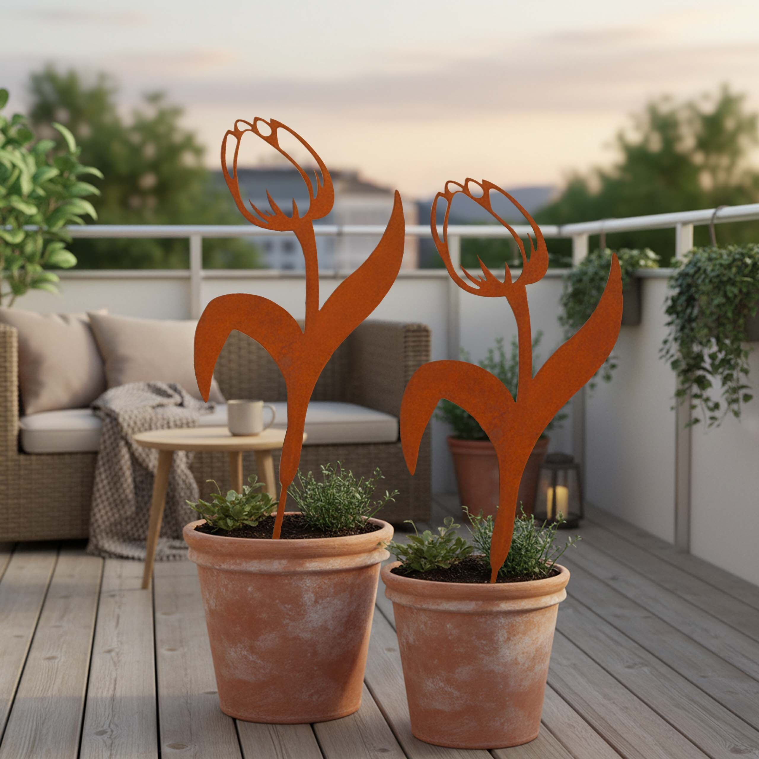 Rostrote Tulpenfiguren aus Metall in Tontöpfen auf einer Holzterrasse mit Möbeln im Hintergrund.
