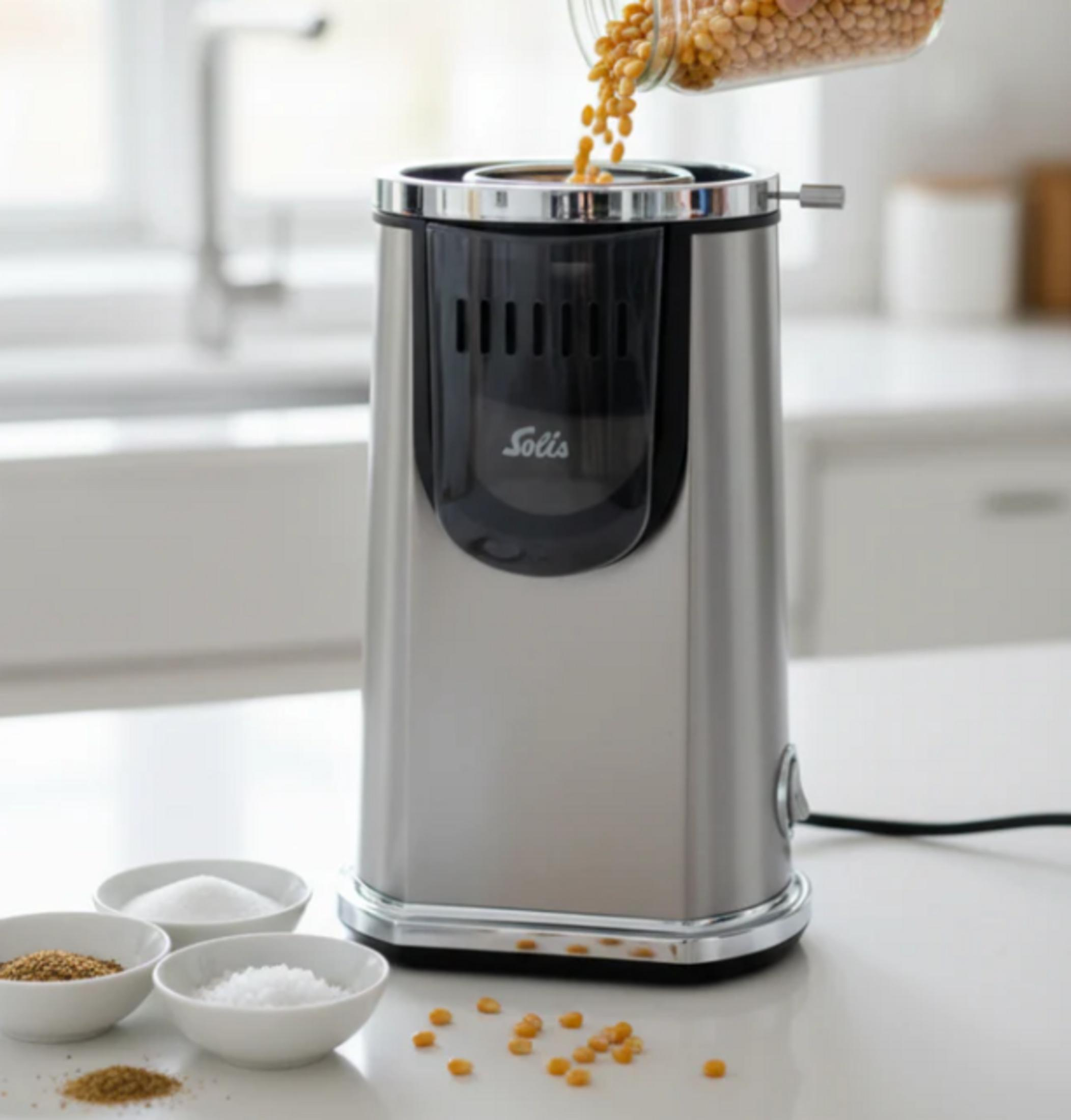 Mulino per cereali su un bancone della cucina con ciotole e chicchi di mais.