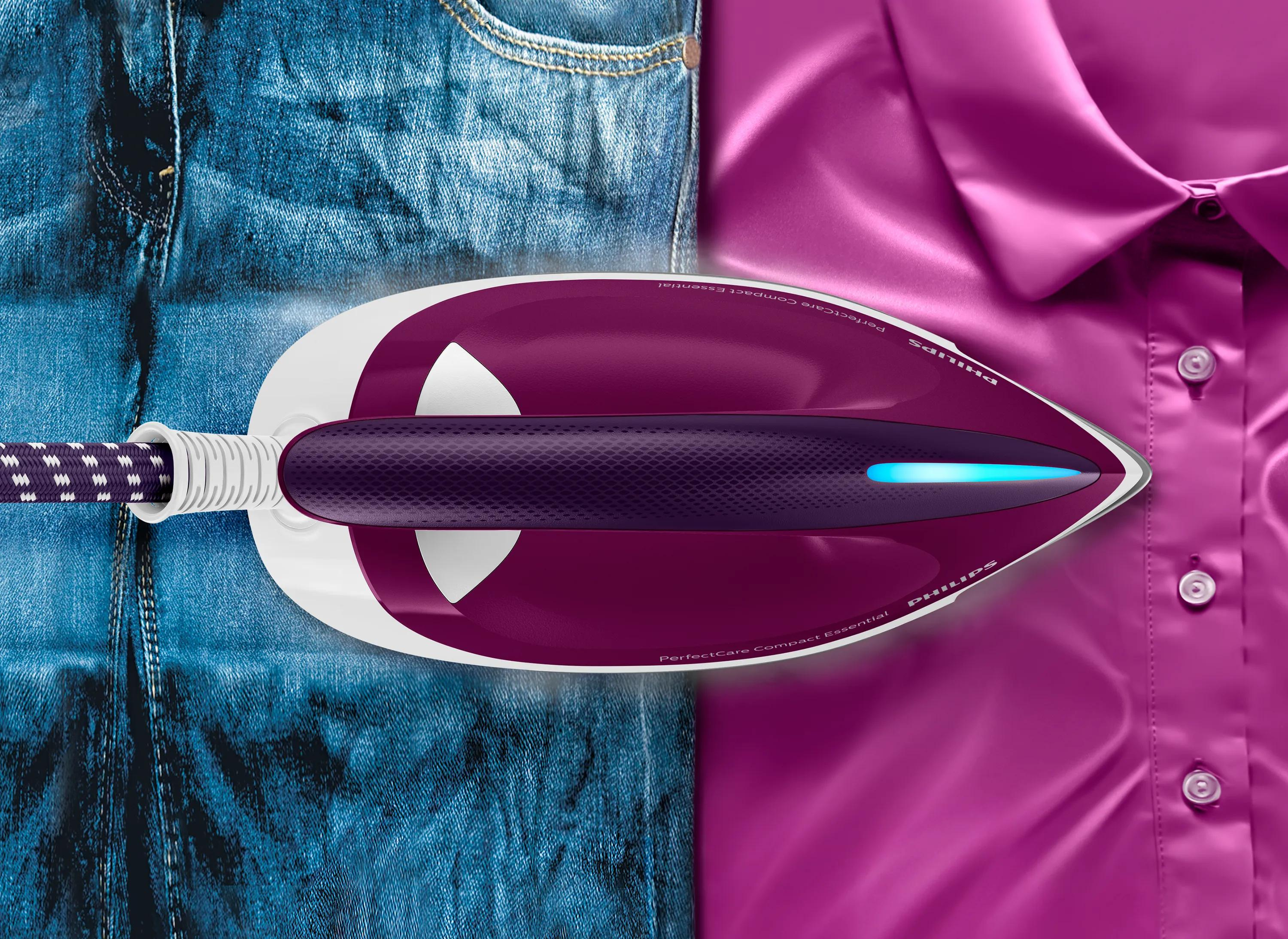 Una plancha morada descansa a mitad de camino entre unos vaqueros azules y una camisa rosa.