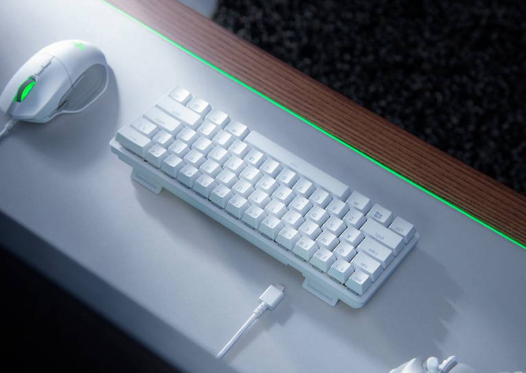 Een wit toetsenbord en muis op een licht bureau met een groene LED-strip.