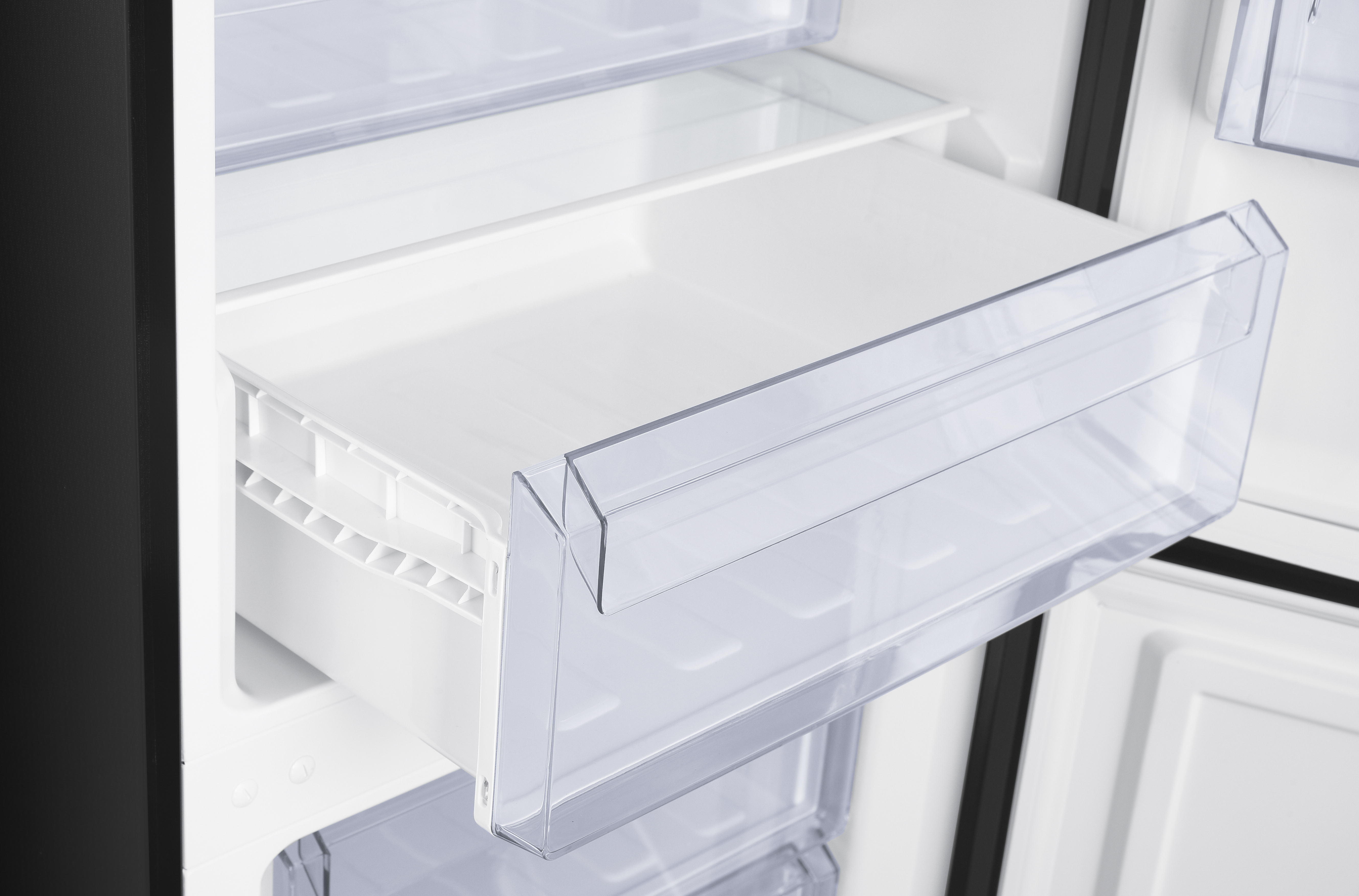 An open refrigerator showing a clear plastic crisper drawer pulled out.