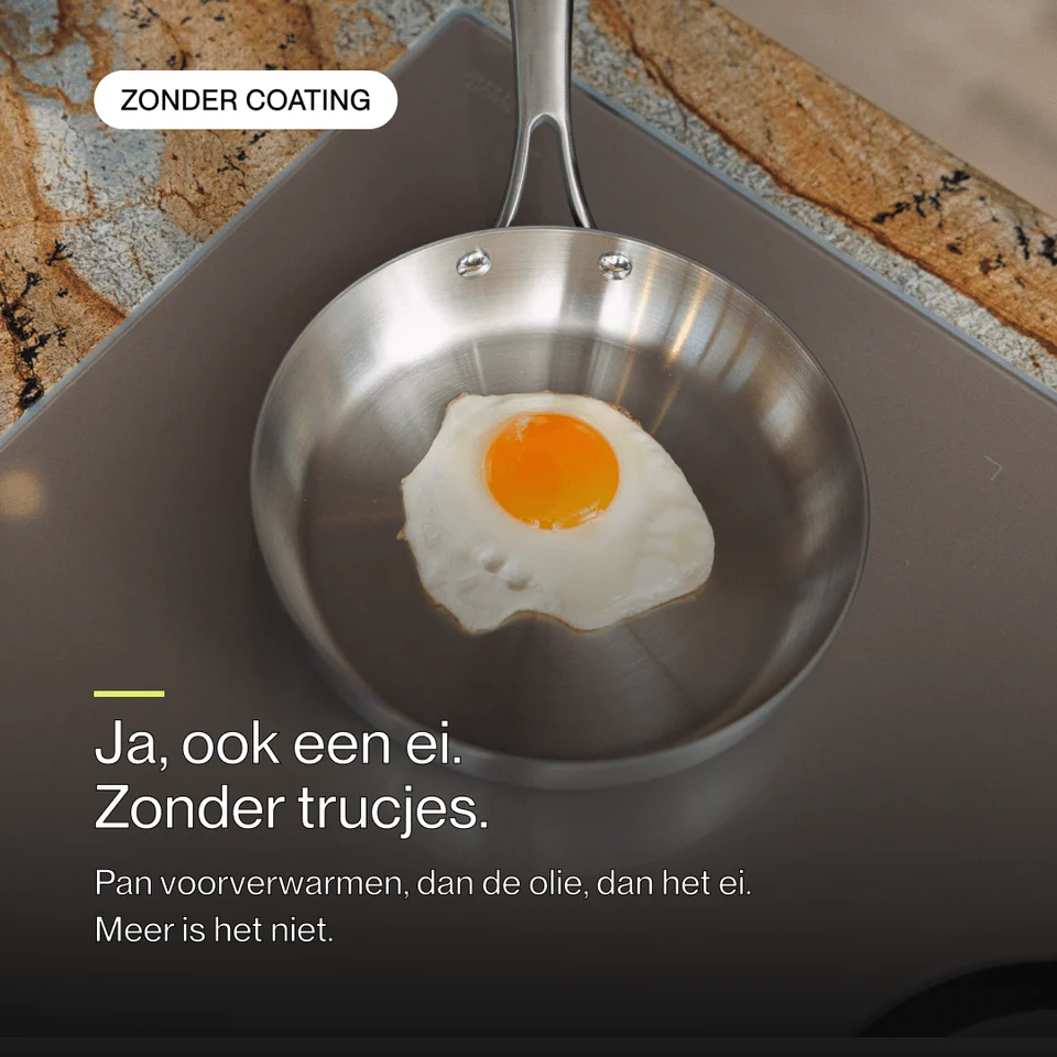 A fried egg is cooking in a shiny stainless steel pan on a stove.