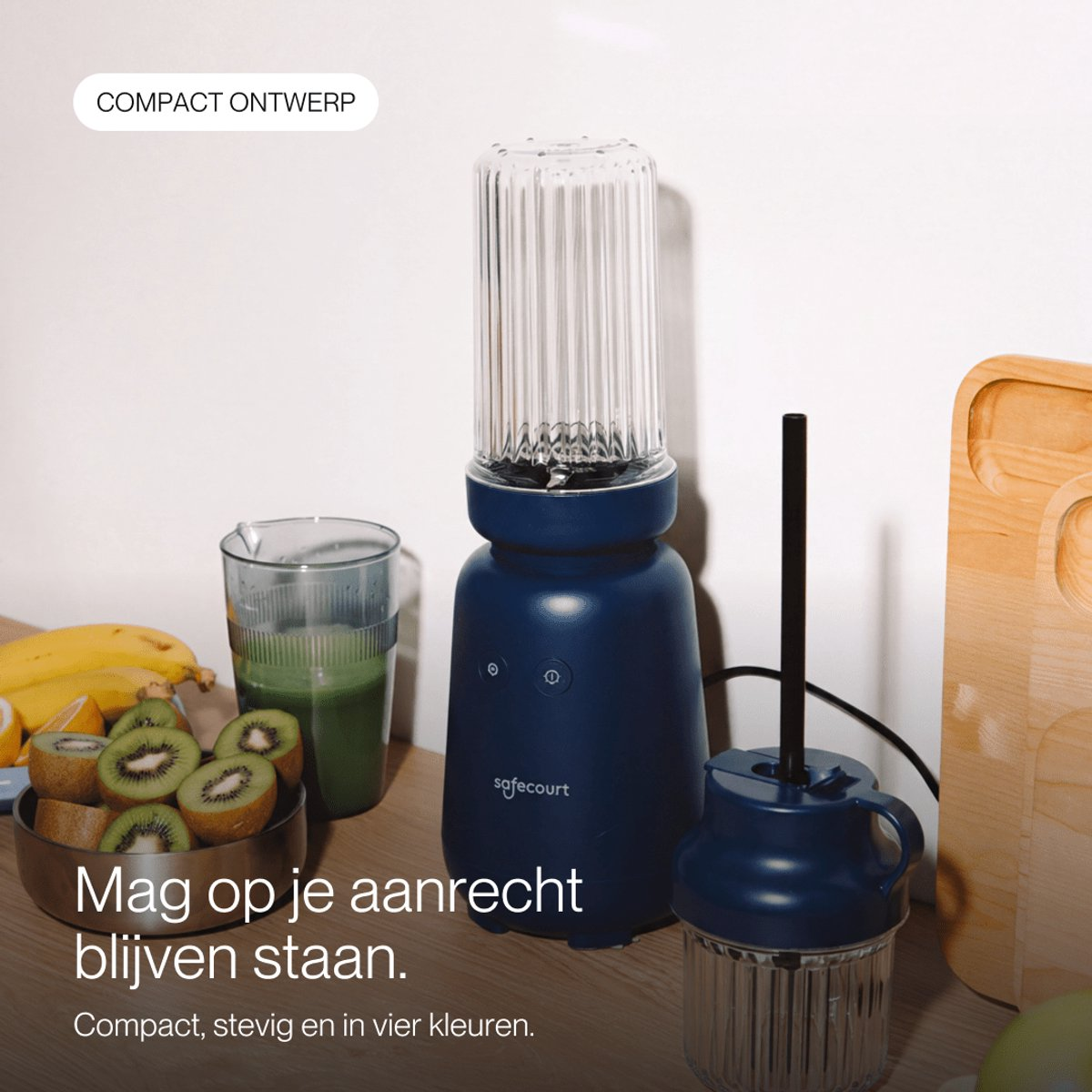 Un blender bleu sur un comptoir de cuisine avec des kiwis tranchés, des bananes et un verre de jus vert.