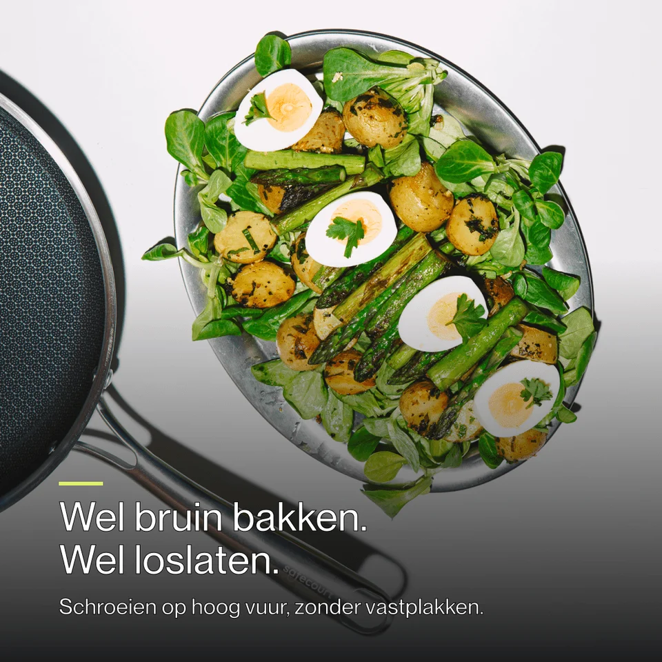 Salad with potatoes, asparagus, and halved eggs on a round platter next to a frying pan.