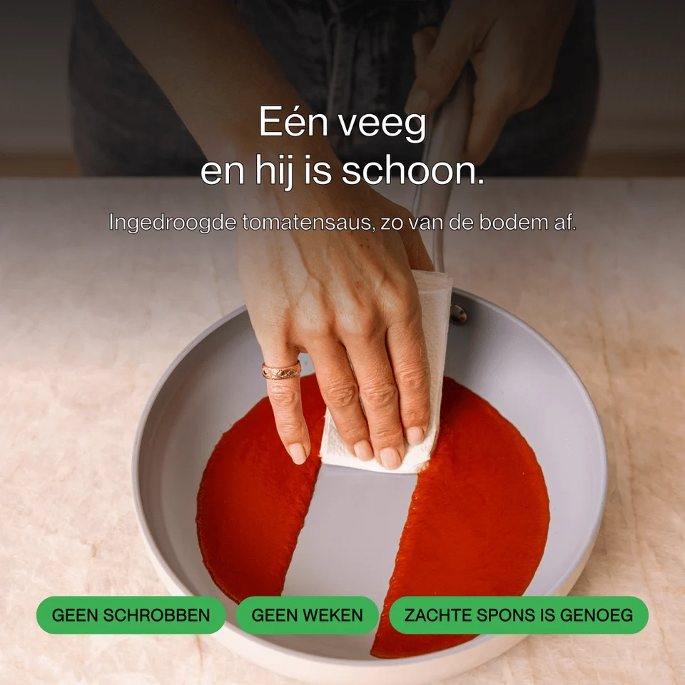 Person wipes tomato sauce from a grey pan with paper.