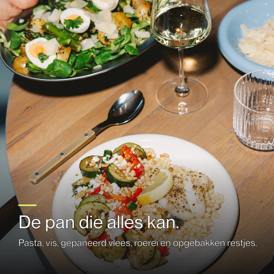 A plate of fish, couscous, and zucchini, with a glass of wine and salad on a wooden table.