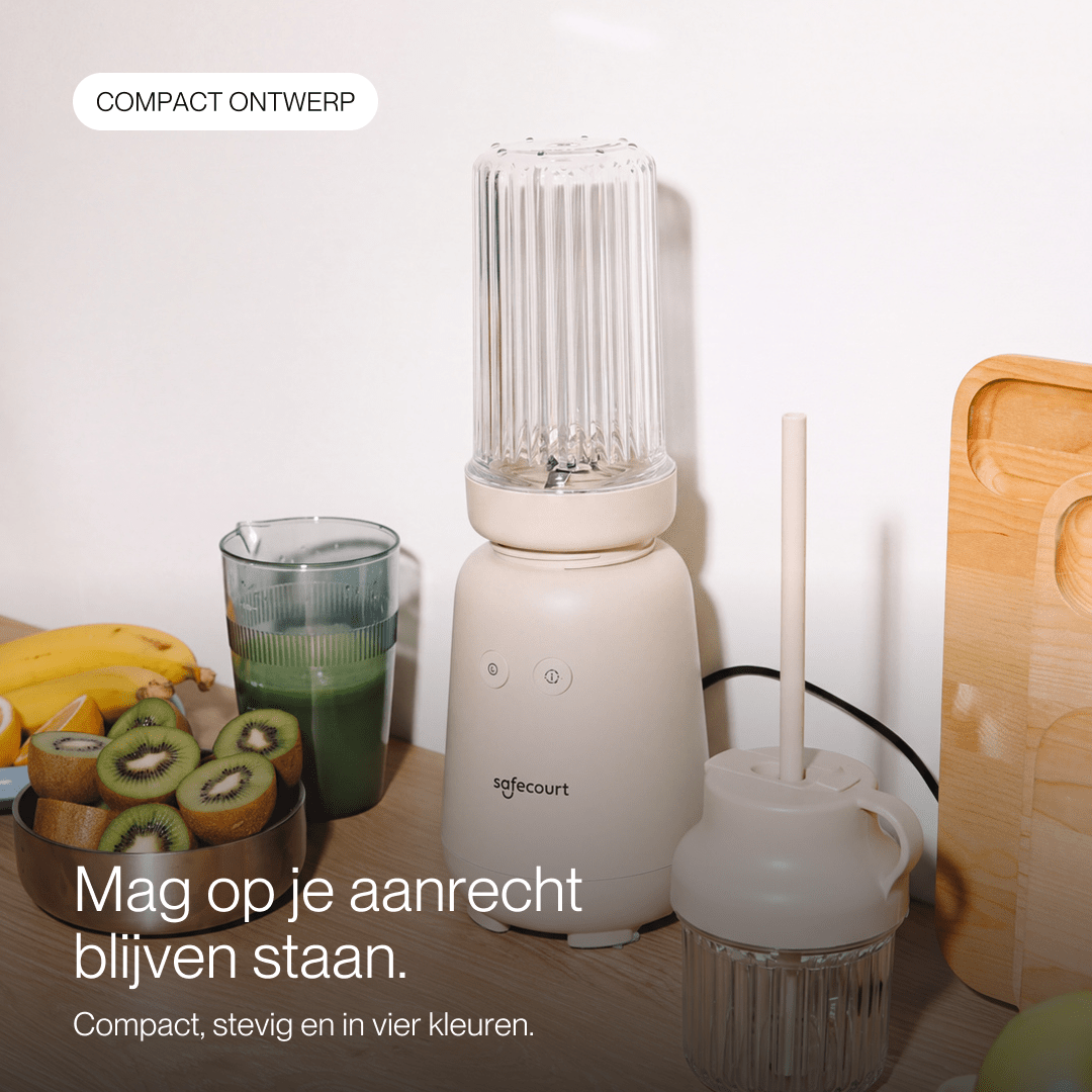Un blender Safecourt beige sur un comptoir avec des kiwis, des bananes et un verre de smoothie vert.