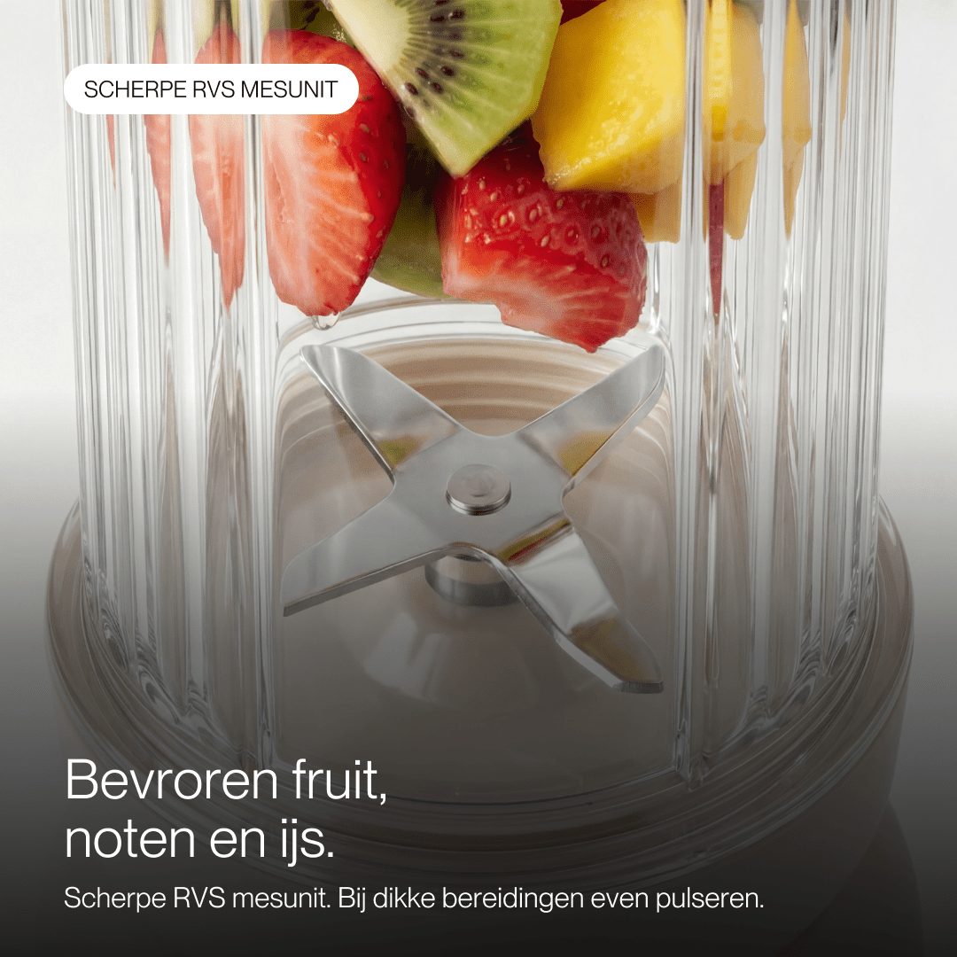 Bol de mixeur rempli de fruits frais et de lames en acier inoxydable.