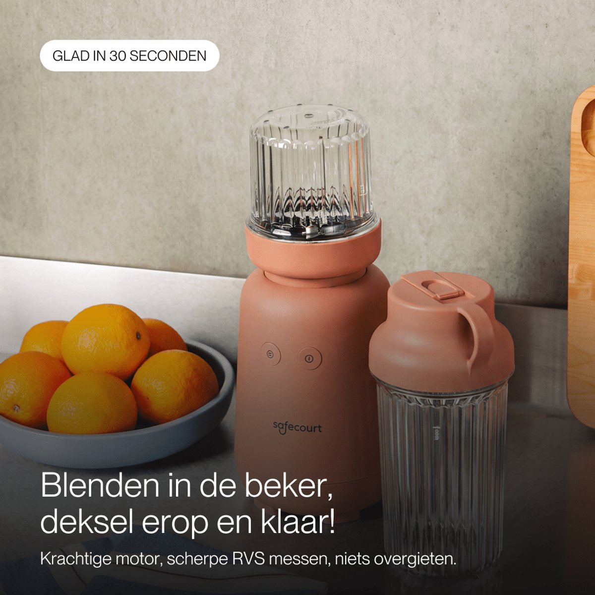 Un blender rose avec un bol d'oranges fraîches sur un plan de travail.