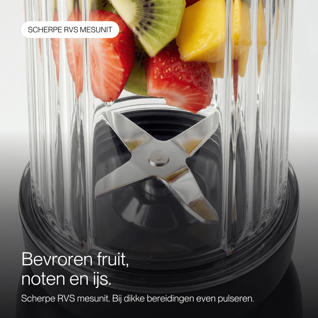 Mixeur avec des fruits frais et des lames en acier inoxydable.