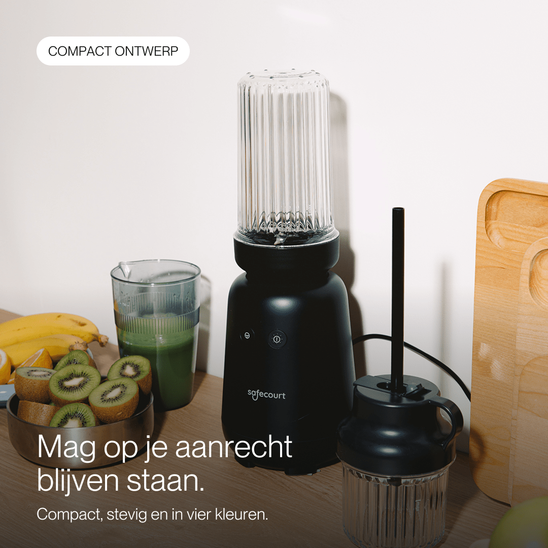 Blender noir Safecourt sur un comptoir avec des kiwis tranchés, des bananes, un verre de smoothie et une planche à découper.