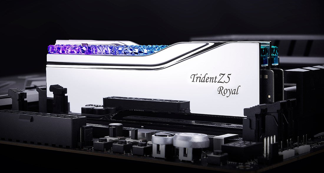 Błyszczący srebrny moduł RAM Trident Z5 Royal z niebieskim i fioletowym podświetleniem RGB na płycie głównej.